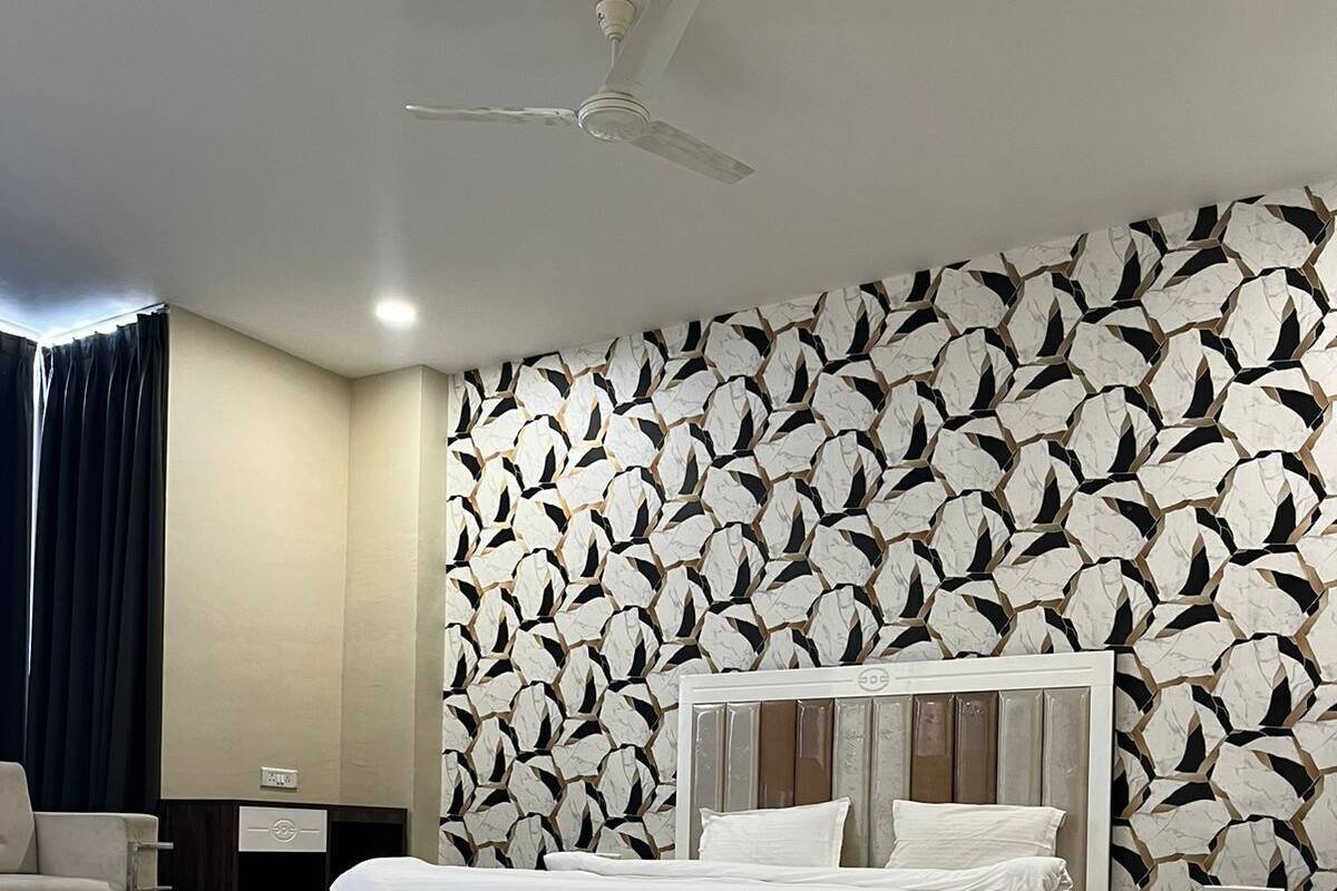 A modern bedroom with a large bed, a ceiling fan, and a patterned wall.