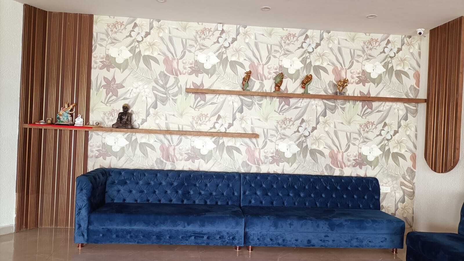 A blue sofa in a room with a floral wallpaper, a wooden shelf with decorative items, and a vertical wooden panel on the left.