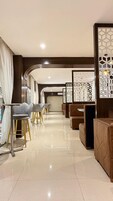 Un moderno vestíbulo de hotel con una zona de estar curva, un mostrador de recepción y separadores decorativos.