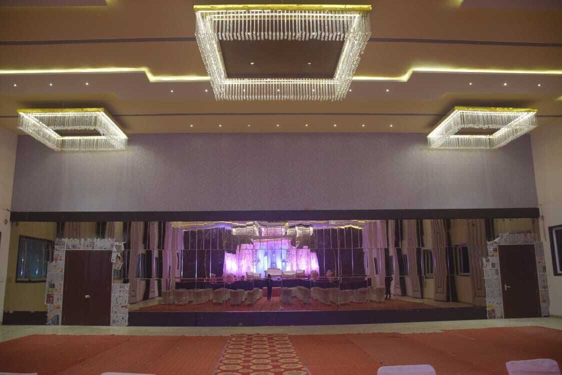 A spacious hall with a stage, seating, and a chandelier.