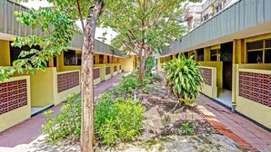 Un patio con edificios amarillos, árboles y un camino.