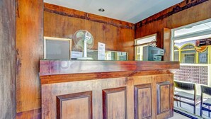Un mostrador de recepción con detalles de madera, un ventilador y un letrero que indica un punto de información turística.
