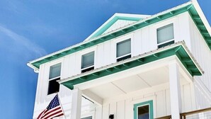 A two-story white house with a balcony, an American flag, and a bicycle parked in front.