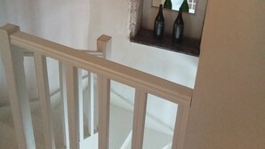 A staircase with a wooden handrail and a small alcove with a mirror and two bottles. - Grand old Villa with pool in the heart  of  Capestang town (on the Canal du Midi) (Capestang)