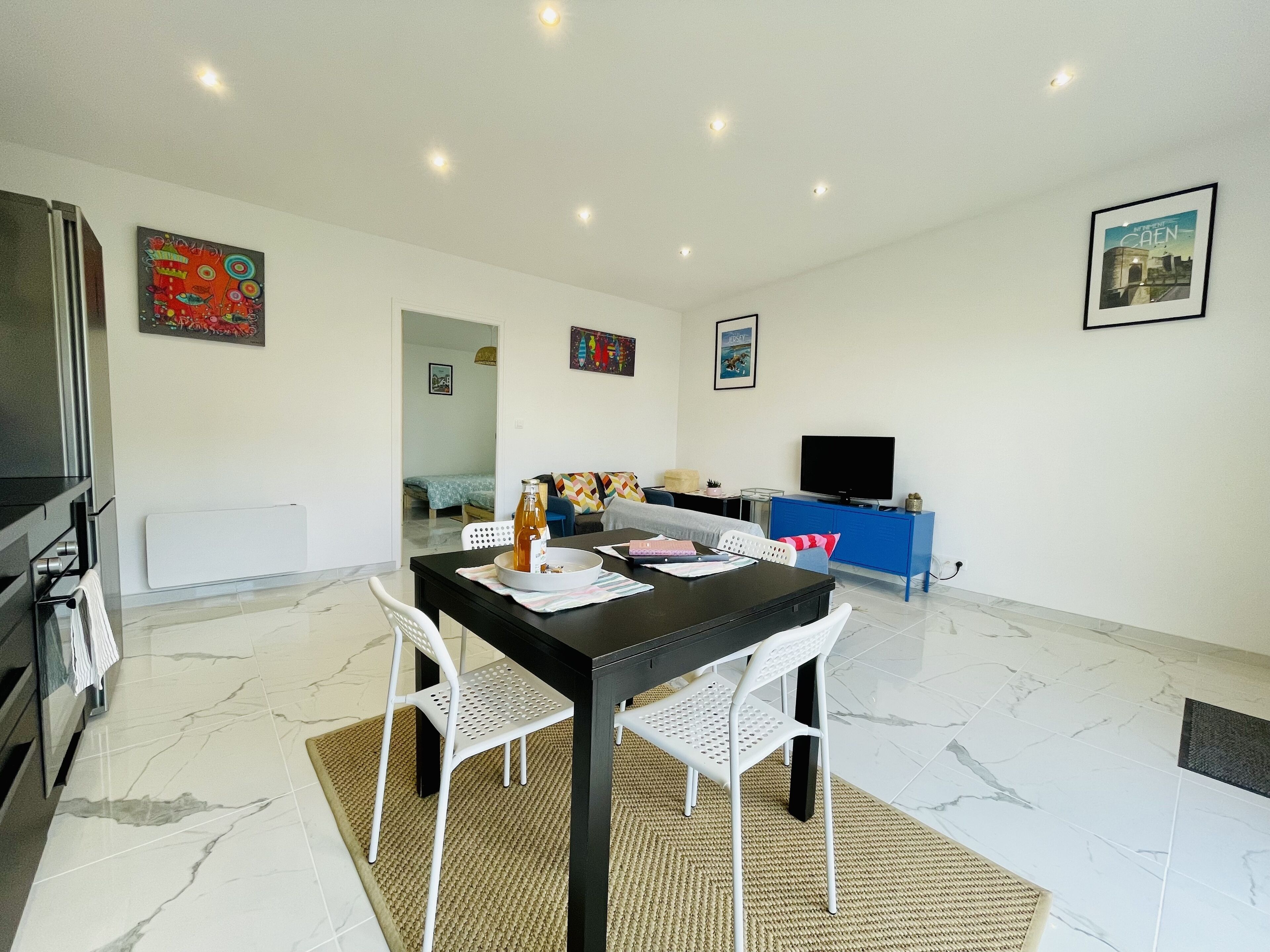 A modern living room with a dining area, a TV, and artwork on the walls.