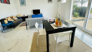 Ein modernes Wohnzimmer mit einer Couch, einem Esstisch und einem Fernseher.