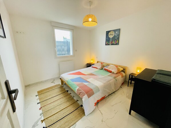 A bedroom with a bed, bedside lamps, a window, a wall art piece, and a black dresser. - Villa with private jacuzzi 500m from the sea (Blainville-sur-Mer)