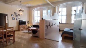 Un amplio salón con un comedor de madera, televisión y un separador de vidrio que dice "Madrid".