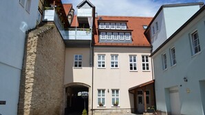 Un edificio europeo tradicional con fachada de piedra, múltiples ventanas y techo de tejas rojas.