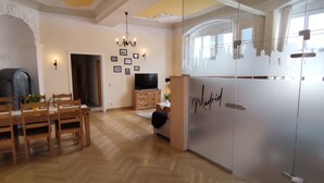 Amplia habitación con comedor, televisor y refrigerador decorado con un motivo de horizonte urbano.