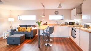 A modern kitchen with white cabinets, a wooden countertop, and stainless steel appliances.