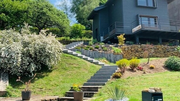 A modern two-story house with a stone staircase leading to the front door.