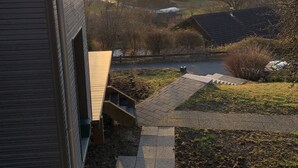 A residential area with a house, a driveway, and a view of distant hills during sunset.