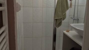 Een badkamer met een douchecabine van glas, een wastafel en een handdoekrek.
