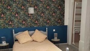 Una camera da letto con un letto, una parete con motivo floreale e una parete d'accento blu.