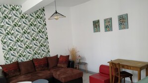 Un soggiorno moderno con un divano componibile, un tavolino da pranzo e un pouf rosso.