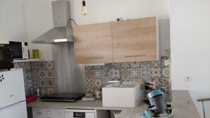 Una cucina compatta con lavatrice, microonde, fornello e lavandino.
