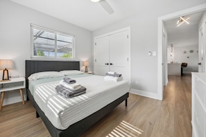 Ein modernes Schlafzimmer mit einem großen Bett, Nachttischen, einem Kleiderschrank und Blick auf ein Badezimmer.