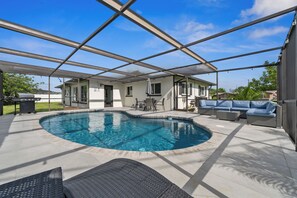 Ein überdachter Außenpool mit Terrassenbereich, Sitzgelegenheiten und einem Grill.