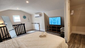 A bedroom with a bed, a TV displaying 'Joyful Moments Vacation Rentals', a wardrobe, and a small desk with a chair. - #79 The Summer Loft by Joyful Moments Vacations (Clearwater)