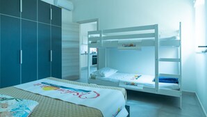 Hotellihuone, jossa on kerrossängyt, vaatekaappi ja sänky peitolla.