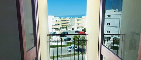 A balcony with a view of a residential area and the sea.