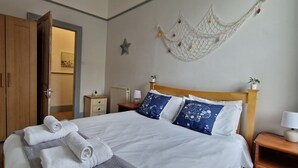 Una cama bien tendida con almohadas blancas y azules, un cabecero de madera y una mesita de noche con una lámpara.