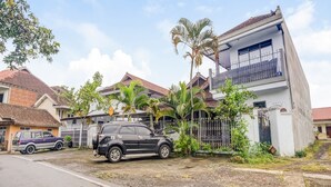 Zona residencial com casas, um SUV preto e um edifício branco com varanda.