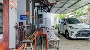Uma área de estacionamento coberta com um carro branco, um balcão de recepção e um banco.