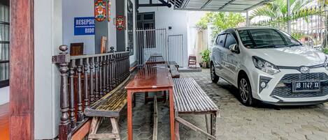 Un área de estacionamiento techada con un coche blanco, un mostrador de recepción y un banco.