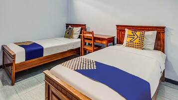 A hotel room with two single beds, a wooden nightstand, and a small table.