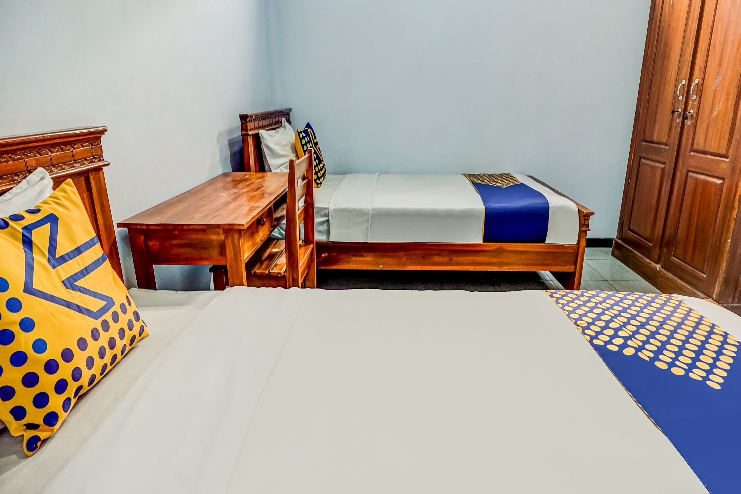 Una habitación con una cama, un escritorio de madera y un armario.