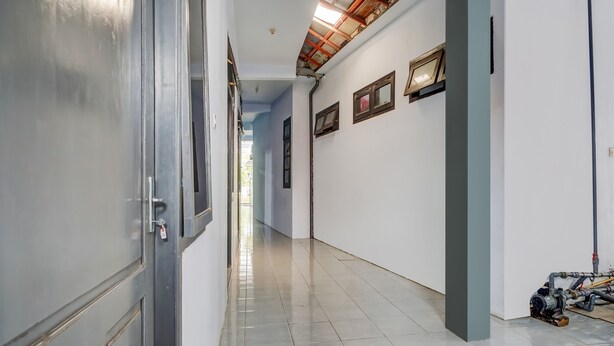 Um corredor com piso ladrilhado, uma porta à esquerda e um aquecedor de água à direita.