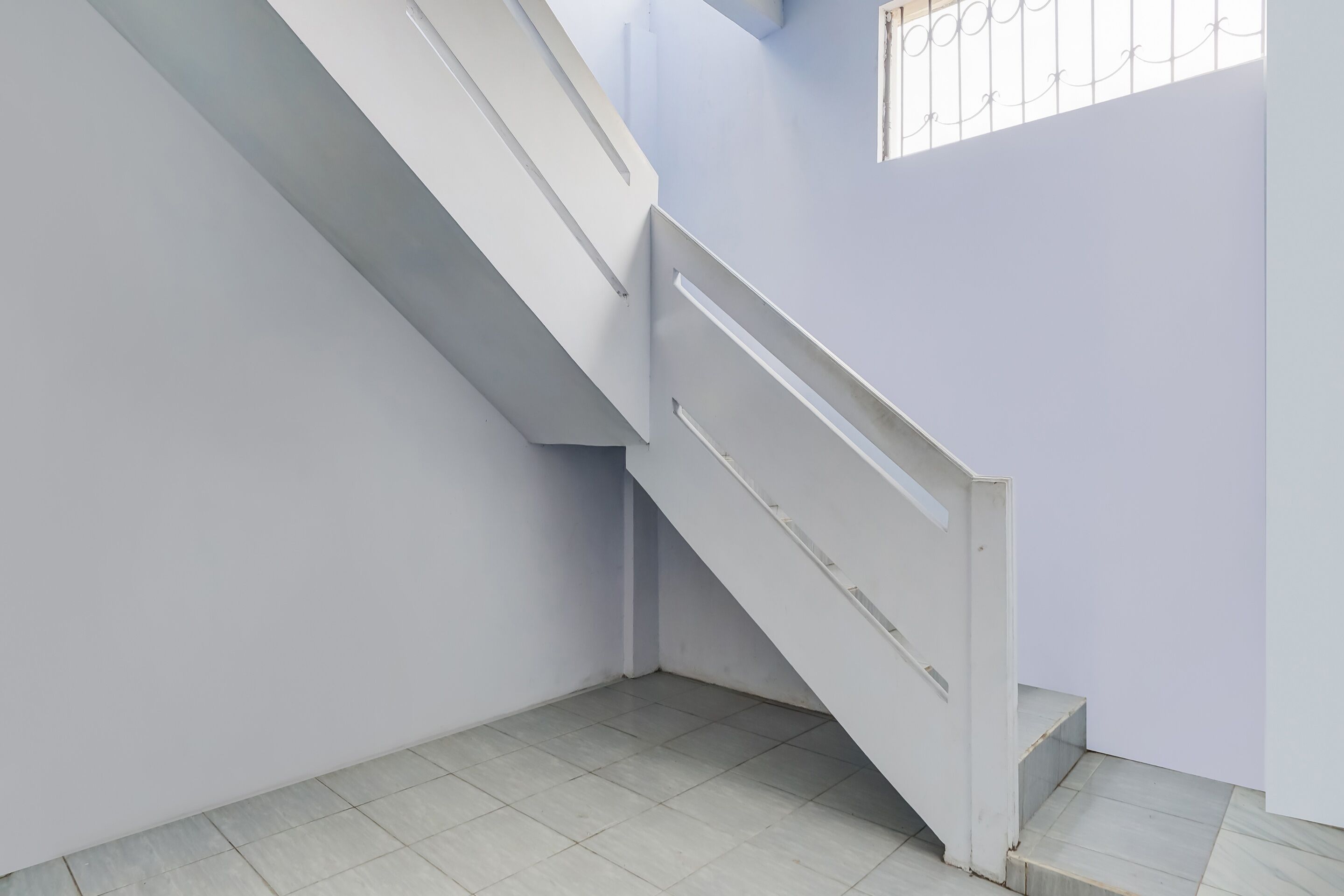 A staircase with white railings and a tiled floor.