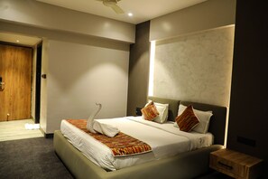 A modern hotel room with a large bed, a wooden nightstand, and a marble wall. - Hotel City Symphony (Nanded)