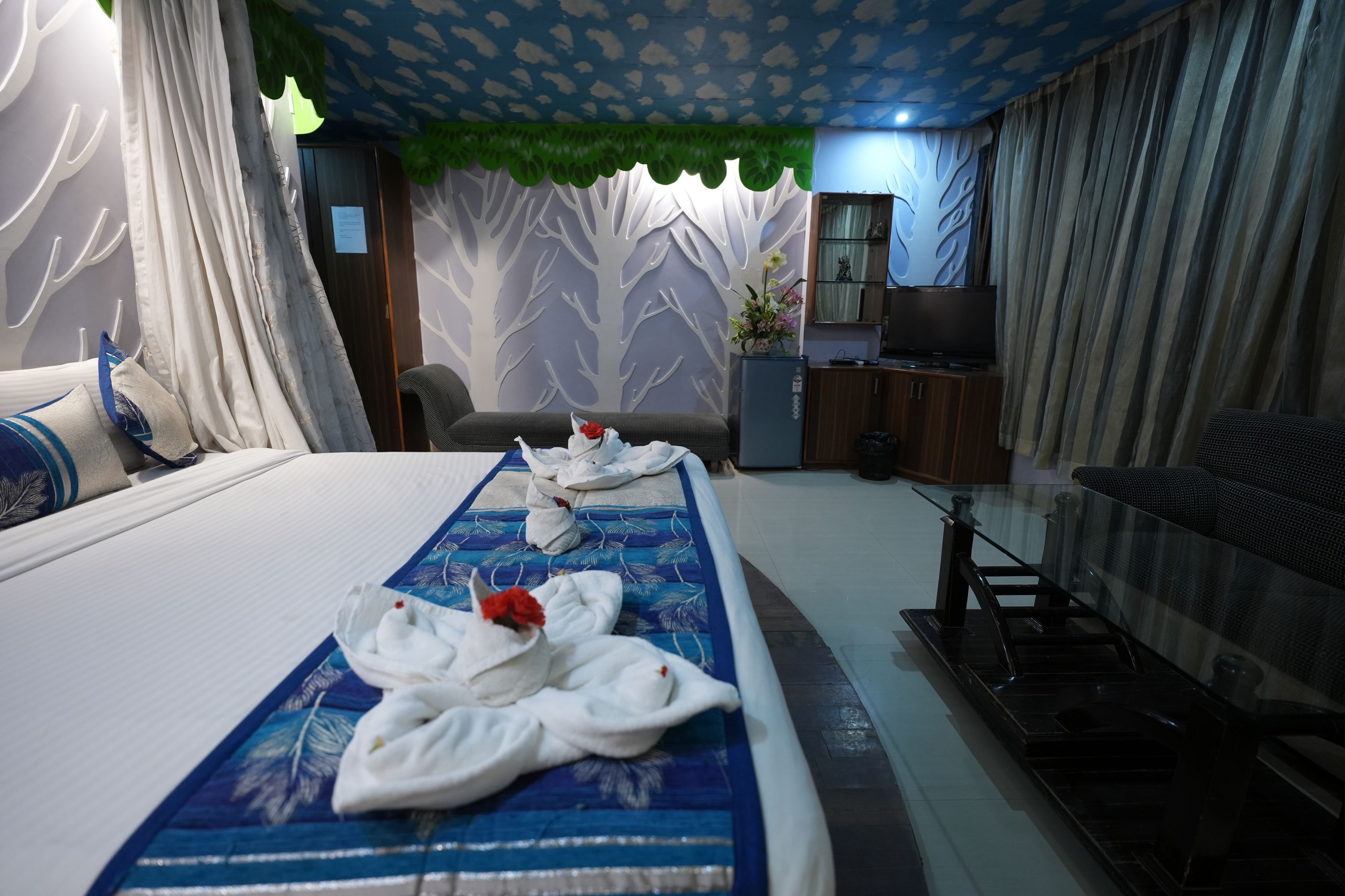 Quarto de hotel com uma cama grande, uma escrivaninha, uma cadeira e uma televisão.