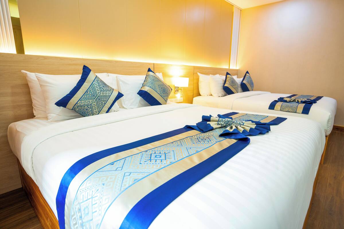 Ein Hotelzimmer mit zwei Betten, jeweils mit weißer Bettwäsche und blauen Zierkissen.
