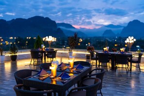 Un espace de restauration en plein air avec des tables et des chaises, un bar et une vue sur les montagnes en arrière-plan.