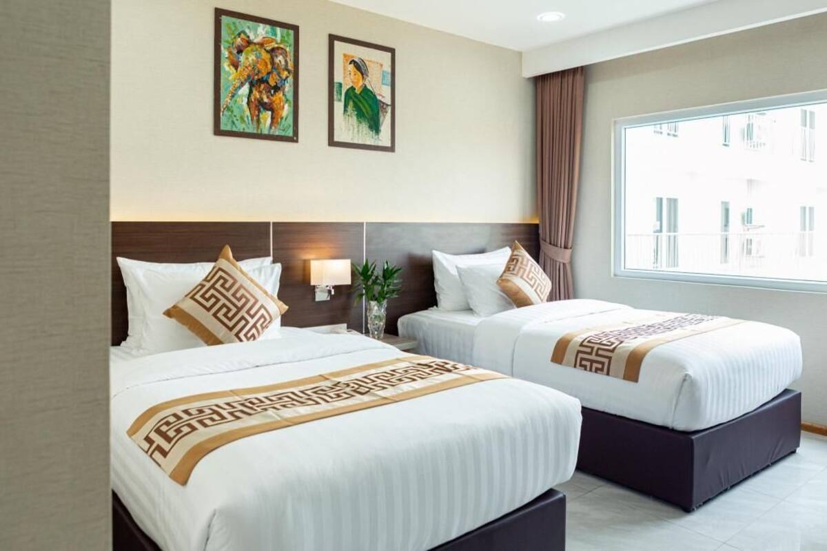 Ein Hotelzimmer mit zwei Betten, einem großen Fenster und einem Kunstwerk an der Wand.