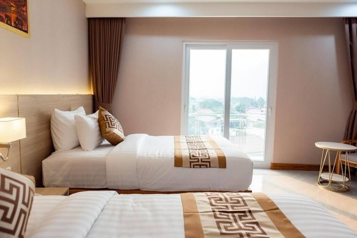 Ein Hotelzimmer mit einem großen Bett, einem kleinen Tisch und Blick auf die Stadt.