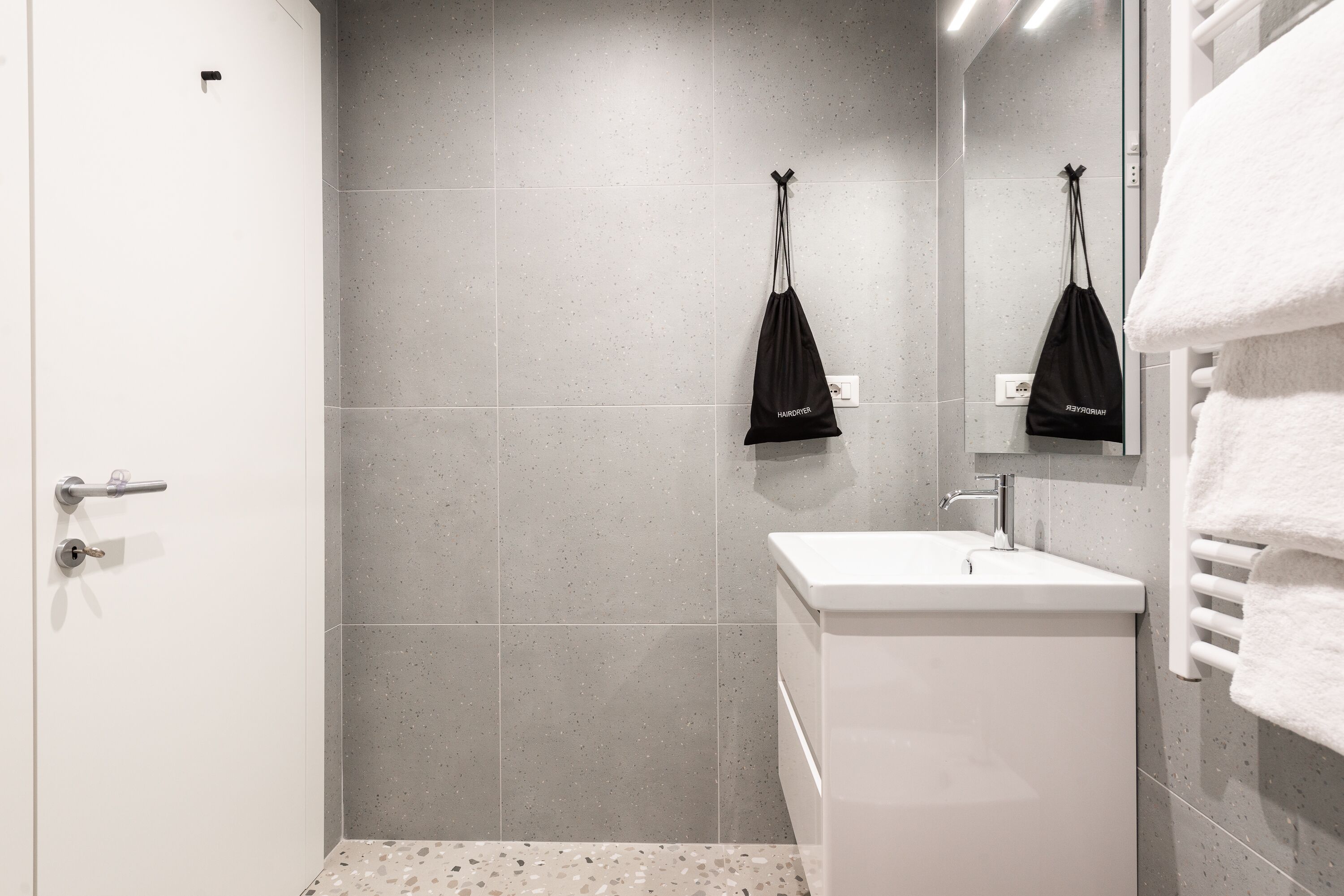 Un baño moderno con ducha, lavamanos y perchero.