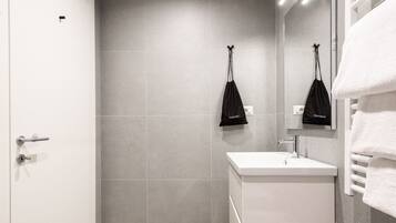 Un baño moderno con ducha, lavamanos y perchero.