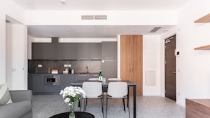 Una cocina moderna con armarios grises, una mesa de comedor con sillas y una pequeña mesa de centro con un florero.