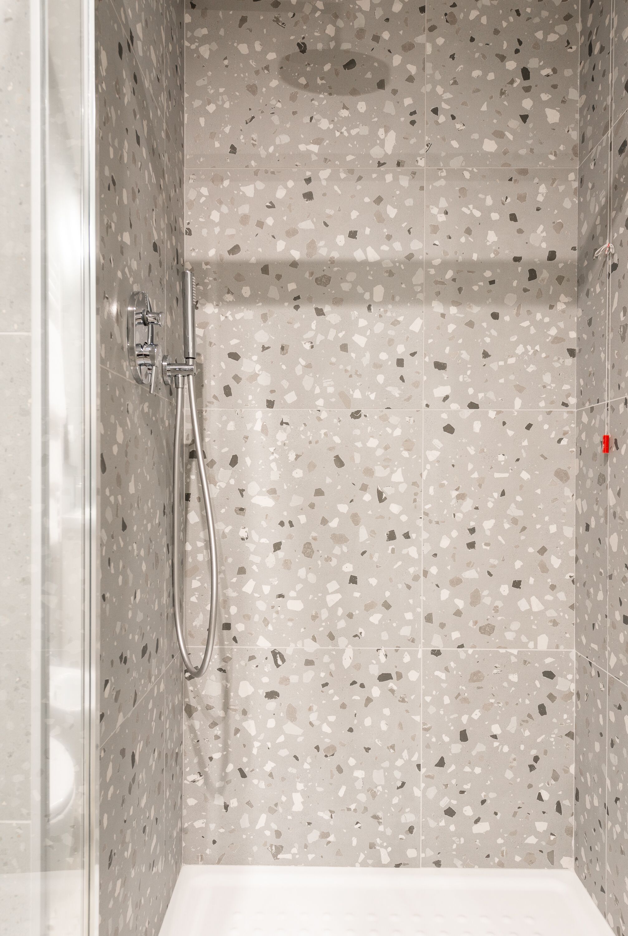 Une douche avec une porte en verre et un pommeau de douche à main.