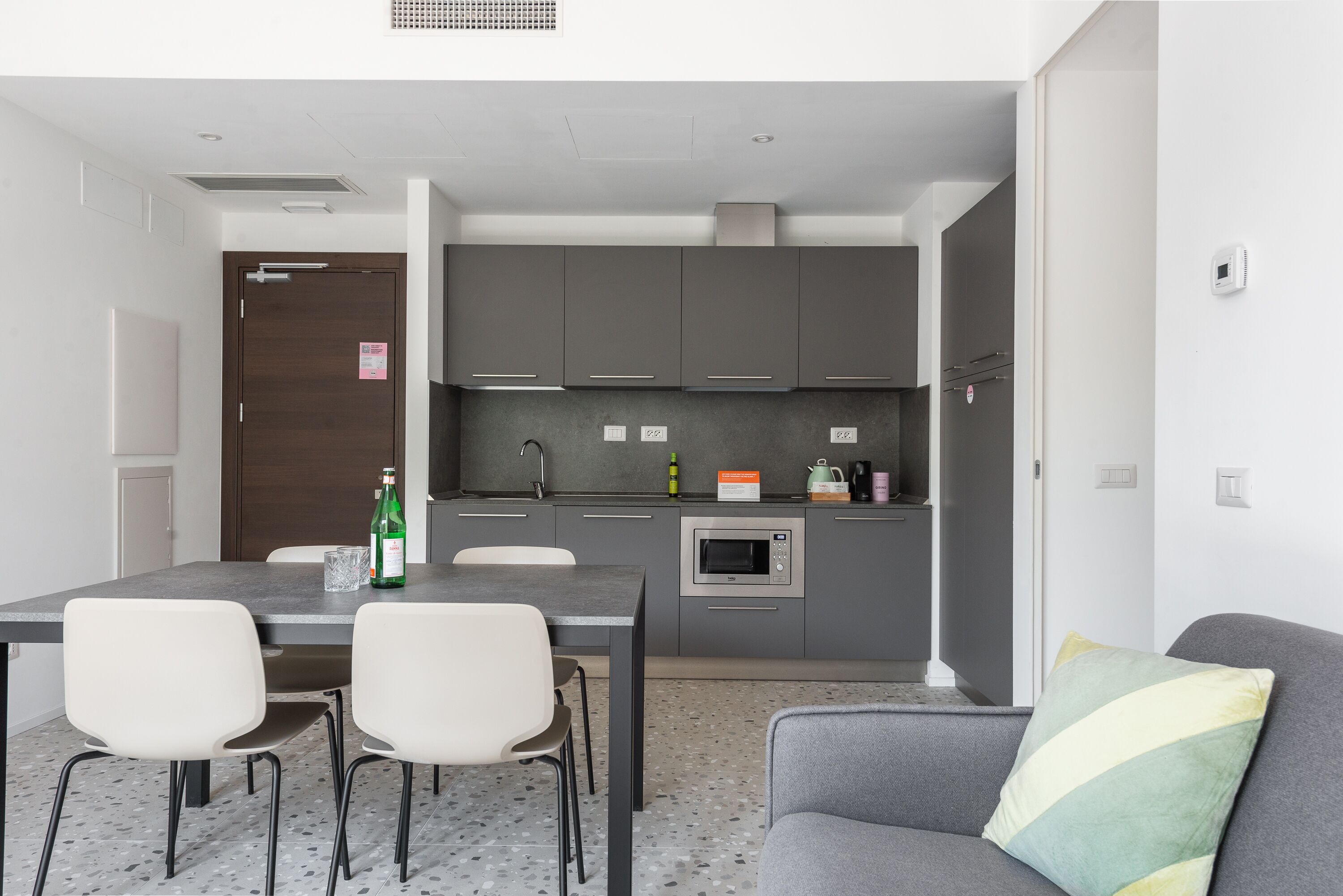 A compact kitchen with a dining area, including a table with chairs, a microwave, and a coffee maker.