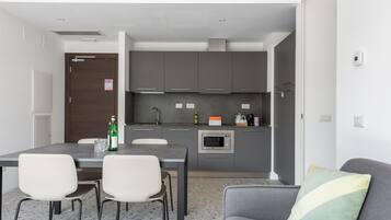 A compact kitchen with a dining area, including a table with chairs, a microwave, and a coffee maker.