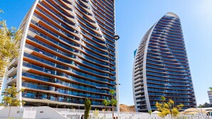 Dos edificios modernos de gran altura con varios balcones, probablemente apartamentos o habitaciones de hotel.