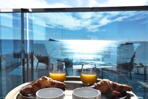 A breakfast tray with croissants, two glasses of orange juice, and a strawberry on a balcony overlooking the sea. - SUNSET DRIVE superb apartment (Alicante)
