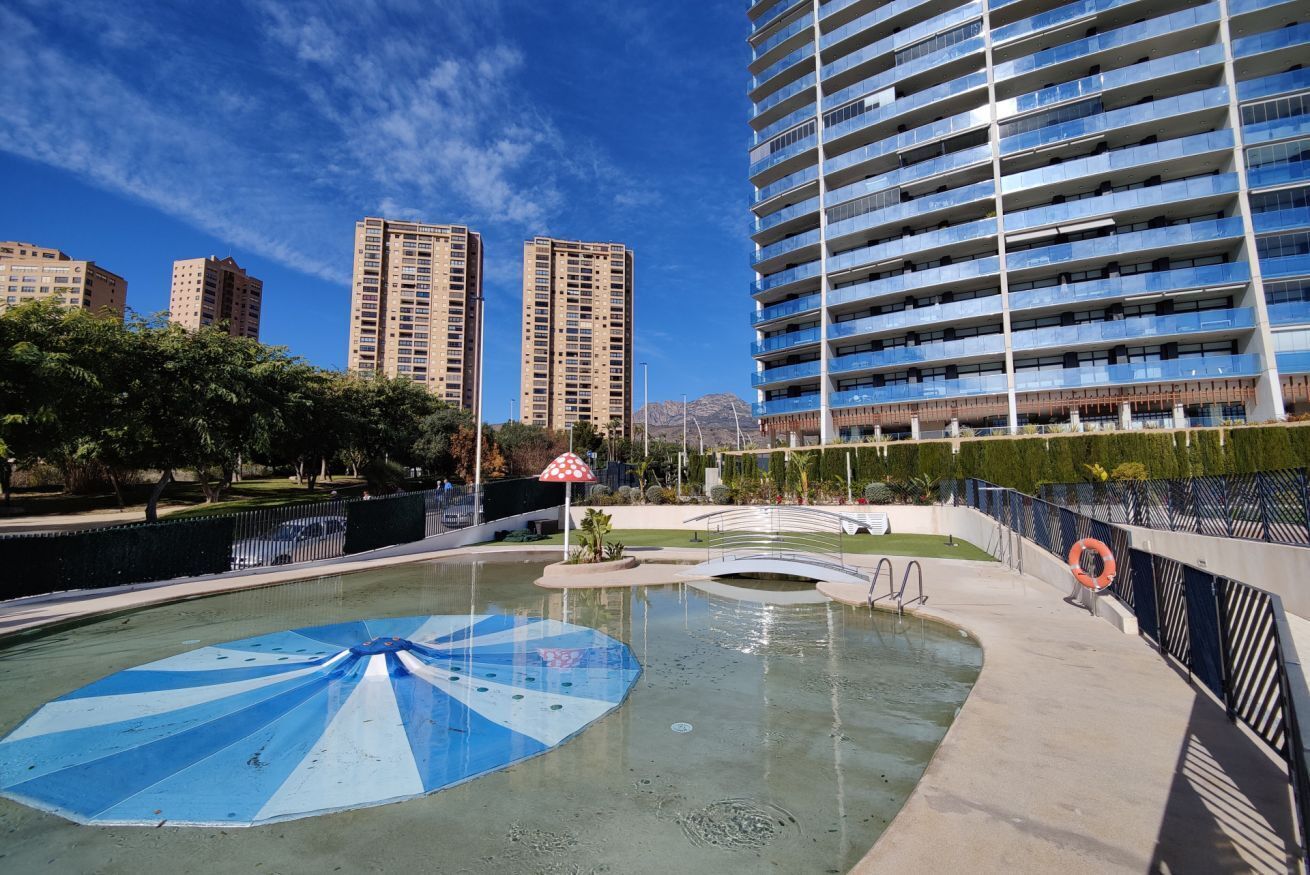 Une piscine avec un parasol bleu et blanc, entourée d’une clôture et agrémentée d’une bouée de sauvetage.