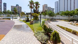 A modern urban area with a paved walkway, palm trees, and tall buildings in the background. - SUNSET WAVES fresh apartments (Benidorm)